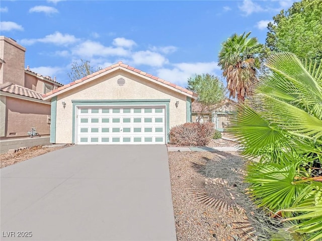 view of front facade featuring driveway, a tiled roof, an attached garage, and stucco siding