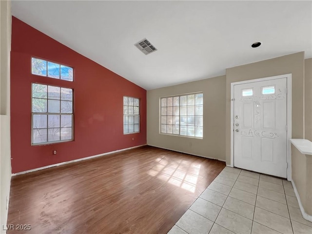 foyer entrance featuring lofted ceiling, light wood finished floors, plenty of natural light, and visible vents