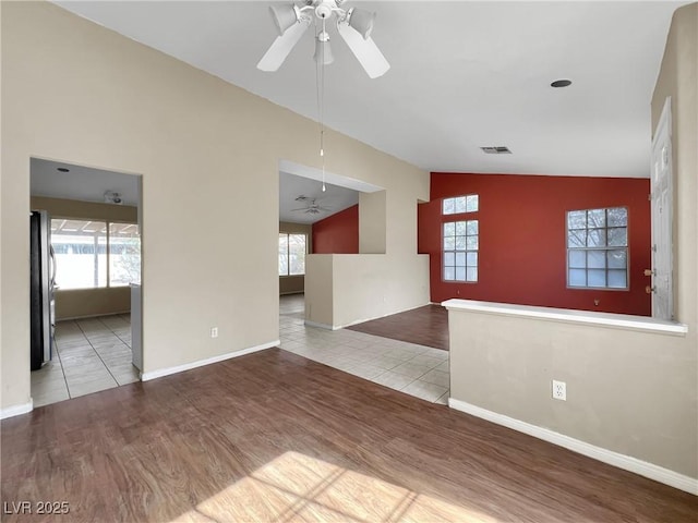 unfurnished living room featuring ceiling fan, a wealth of natural light, vaulted ceiling, and wood finished floors