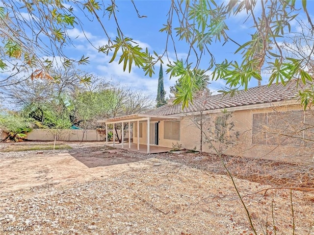 exterior space with a patio area, fence, and stucco siding