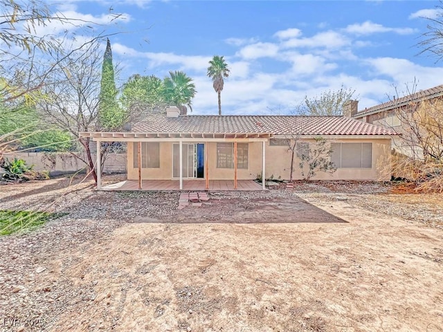 rear view of property with a patio area, a tiled roof, a chimney, and stucco siding