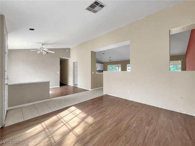 interior space with ceiling fan, visible vents, vaulted ceiling, and wood finished floors