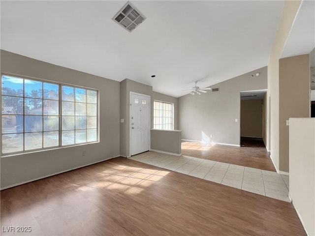 interior space with visible vents, baseboards, vaulted ceiling, a ceiling fan, and light wood finished floors