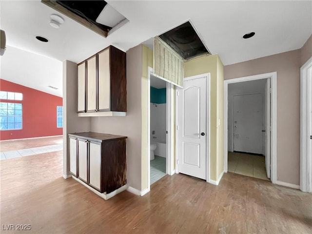 hall with vaulted ceiling, light wood finished floors, and baseboards