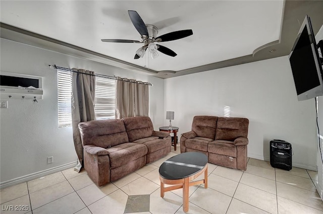 living room featuring light tile patterned floors, a tray ceiling, baseboards, and a ceiling fan