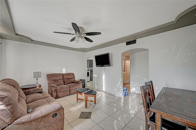 living area featuring arched walkways, a raised ceiling, visible vents, and light tile patterned floors