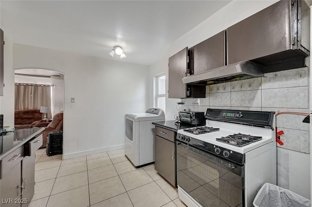 kitchen featuring range with gas stovetop, arched walkways, tasteful backsplash, washer / clothes dryer, and light tile patterned flooring