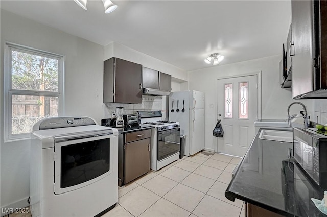 kitchen with light tile patterned floors, tasteful backsplash, dark countertops, washer / dryer, and white appliances