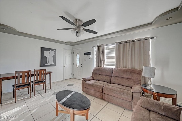 living area featuring light tile patterned floors, a tray ceiling, a ceiling fan, and baseboards