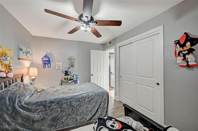 bedroom featuring light wood finished floors, visible vents, and a ceiling fan