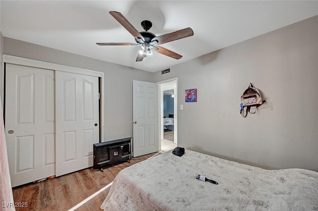 bedroom with ceiling fan, a closet, visible vents, and wood finished floors