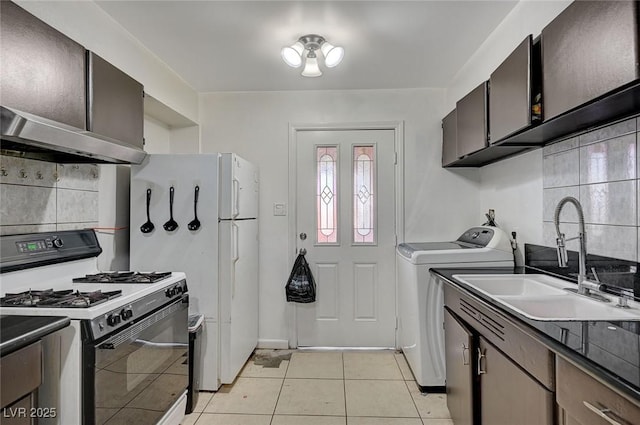 kitchen featuring washing machine and dryer, a sink, decorative backsplash, and gas range