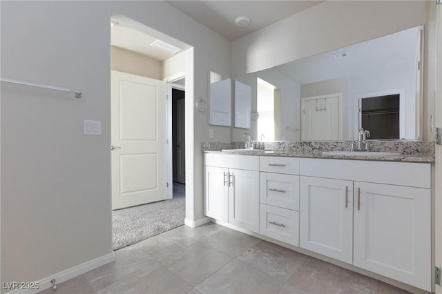 full bath with a sink, baseboards, and double vanity