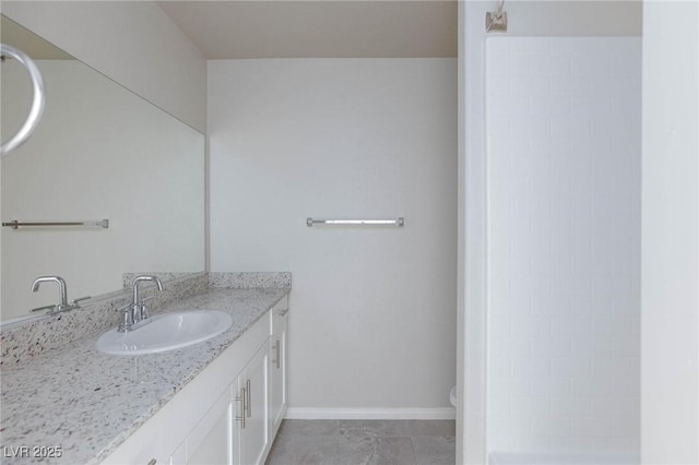 bathroom featuring baseboards, walk in shower, and vanity