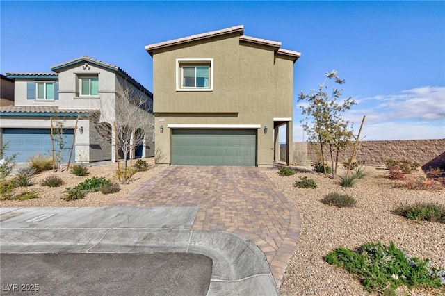 view of front facade featuring decorative driveway, an attached garage, and stucco siding