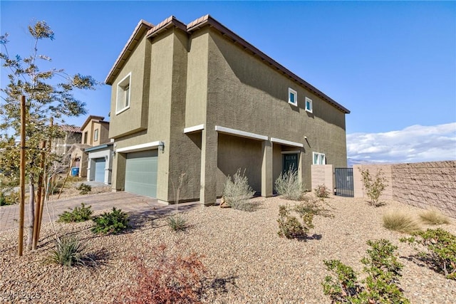 view of side of property featuring a garage, fence, driveway, and stucco siding