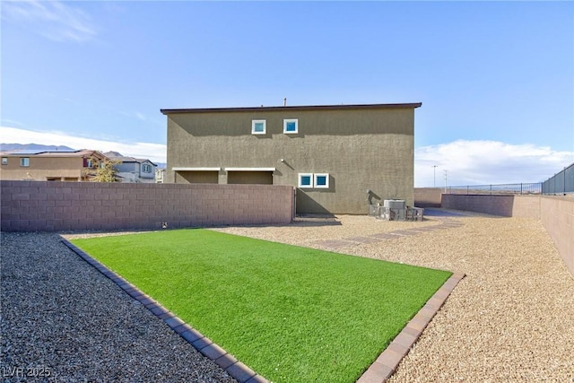 rear view of property featuring central AC unit, a lawn, a fenced backyard, and stucco siding