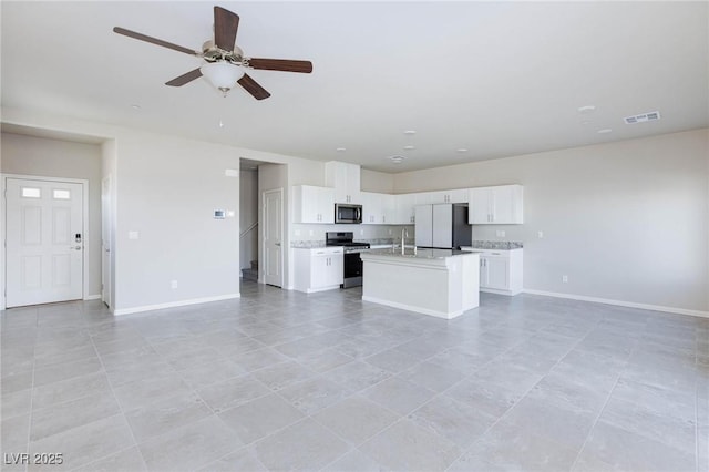 kitchen featuring visible vents, appliances with stainless steel finishes, open floor plan, light countertops, and a sink