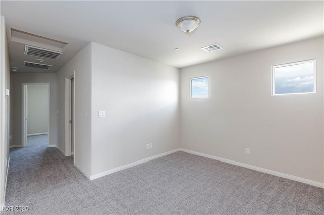 empty room with carpet, visible vents, and baseboards