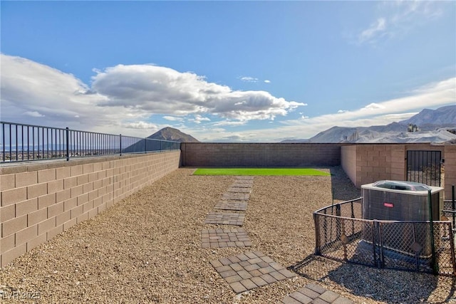 view of yard featuring a fenced backyard, a mountain view, and central air condition unit