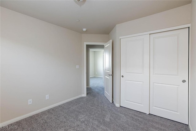 unfurnished bedroom with a closet, carpet, and baseboards