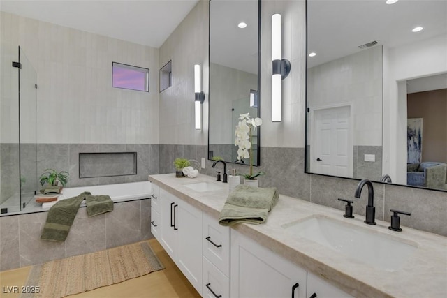 bathroom featuring visible vents, a fireplace, a sink, and tile walls