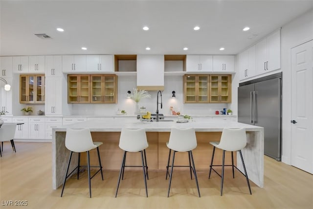 kitchen featuring a spacious island, visible vents, white cabinets, light countertops, and stainless steel built in refrigerator