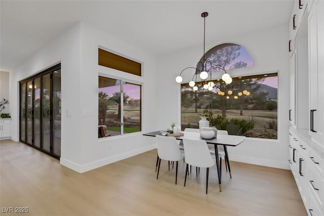 dining room with a chandelier, a healthy amount of sunlight, baseboards, and light wood finished floors