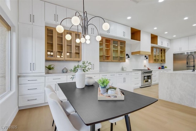 kitchen featuring light countertops, light wood finished floors, glass insert cabinets, and high quality appliances