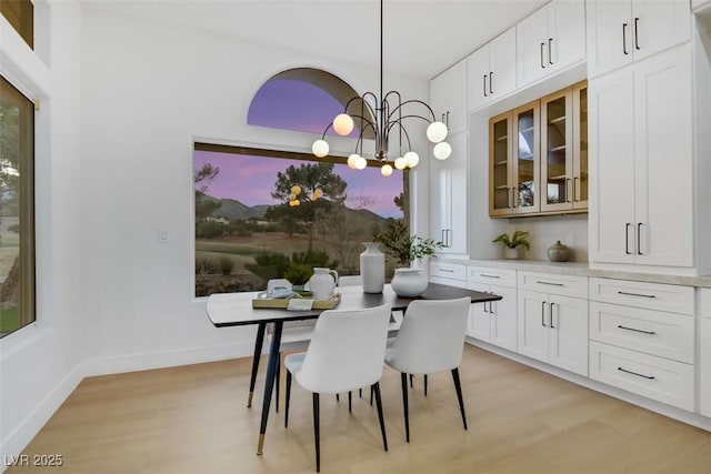 dining room featuring a chandelier, light wood-type flooring, and baseboards