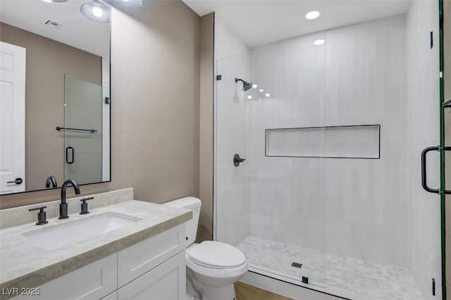 bathroom featuring visible vents, a stall shower, vanity, and toilet