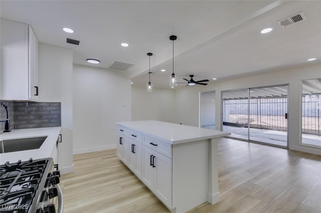 kitchen featuring light wood-type flooring, visible vents, a sink, and backsplash