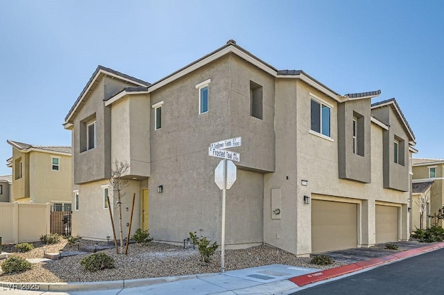 townhome / multi-family property with a garage, fence, and stucco siding