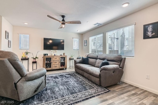 living area with visible vents, a wealth of natural light, and wood finished floors