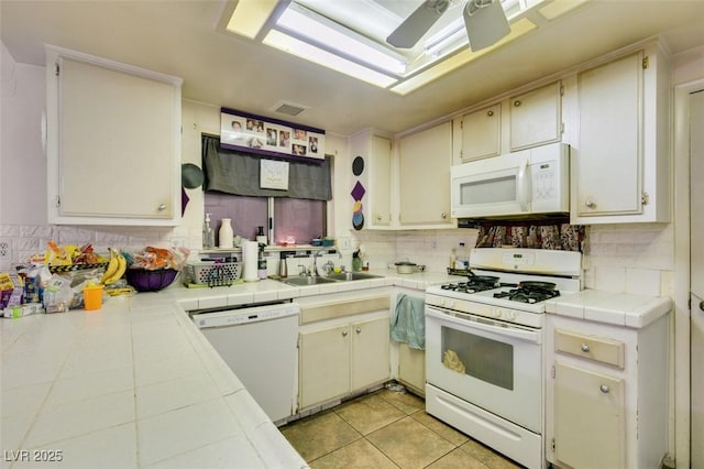 kitchen with tasteful backsplash, white appliances, a sink, and tile countertops