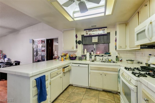 kitchen featuring white appliances, a sink, a peninsula, and backsplash