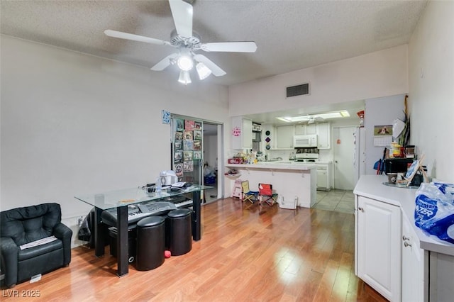 dining room featuring a ceiling fan, visible vents, a textured ceiling, and light wood finished floors