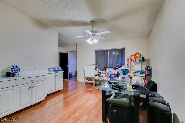 interior space with ceiling fan, a textured ceiling, and light wood-style floors