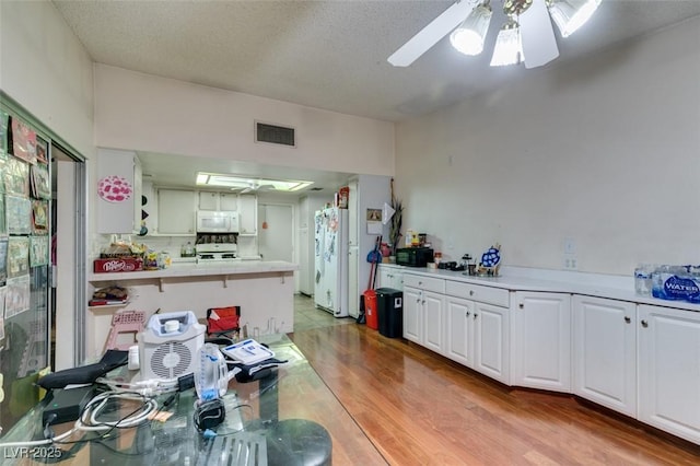 kitchen featuring white appliances, visible vents, a ceiling fan, light countertops, and white cabinetry