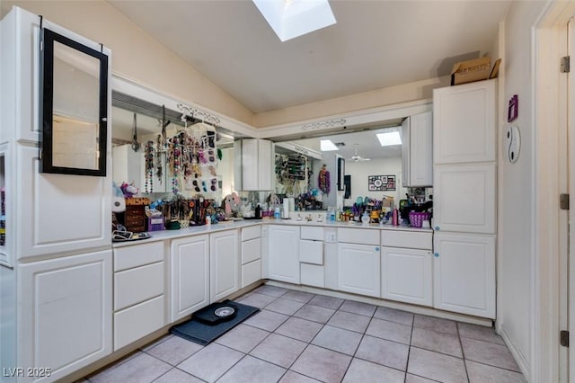 bathroom featuring tile patterned flooring, vaulted ceiling with skylight, and vanity