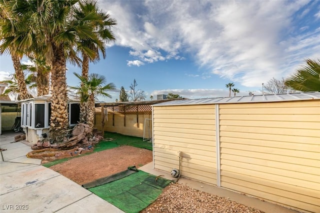 view of side of home with a fenced backyard, a patio, and an outbuilding