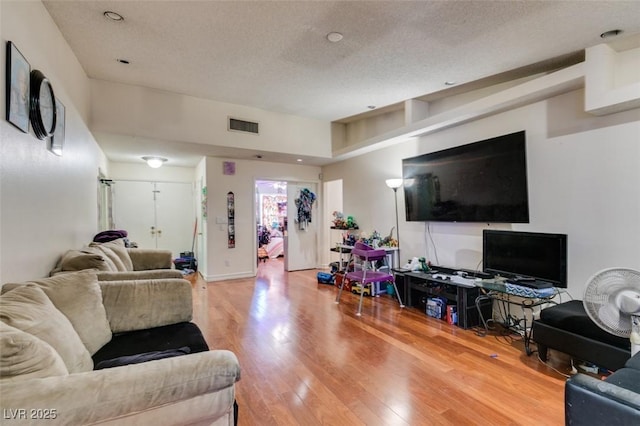 living area featuring visible vents, a textured ceiling, and wood finished floors