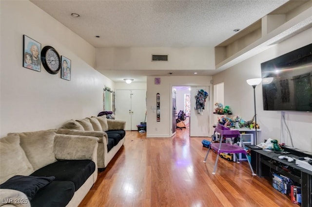 living area featuring a textured ceiling, visible vents, and light wood-style floors