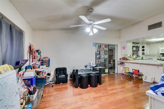 interior space with light wood finished floors, visible vents, ceiling fan, vaulted ceiling, and a textured ceiling