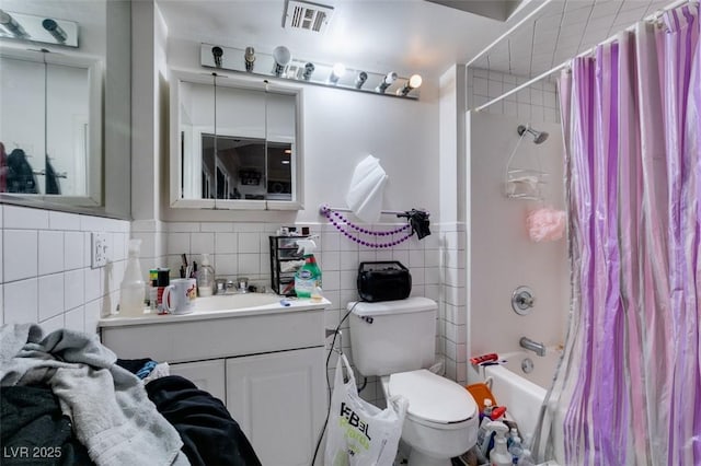 full bath featuring visible vents, toilet, shower / bath combination with curtain, vanity, and tile walls