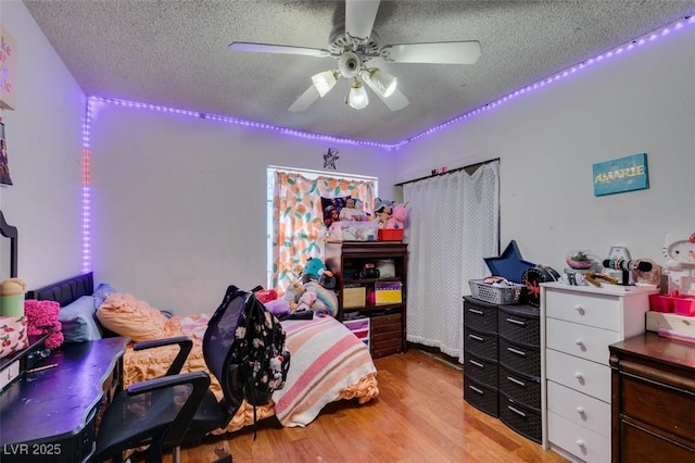 bedroom featuring ceiling fan, light wood-style flooring, and a textured ceiling