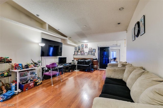 living area with lofted ceiling, a textured ceiling, and wood finished floors