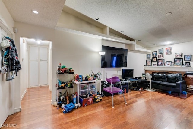 interior space with lofted ceiling, a textured ceiling, wood finished floors, and recessed lighting