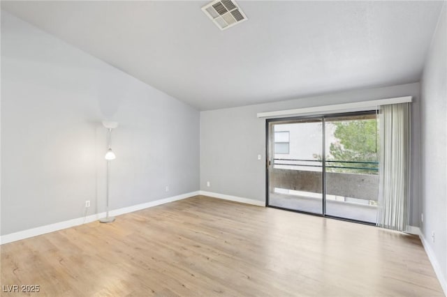 empty room with baseboards, visible vents, and wood finished floors