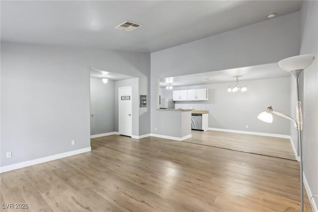 unfurnished living room featuring baseboards, visible vents, an inviting chandelier, vaulted ceiling, and light wood-style floors